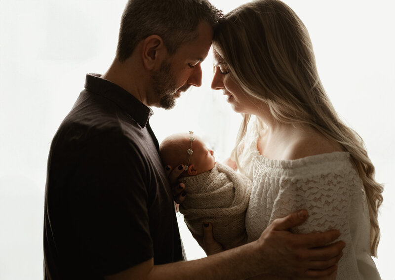 Mother and father holding their newborn in a tender moment during a family session at Duehr Photography studio in Maple Grove.