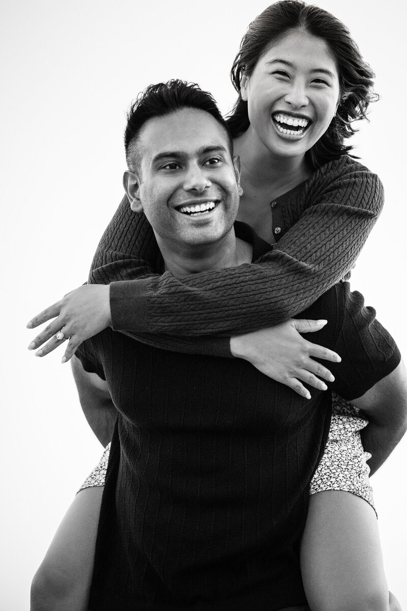 Surprise proposal at Discovery Park, Seattle Washington showing a stunning black and white portrait by Maë Lans Photography of a joyful, newly engaged young couple.