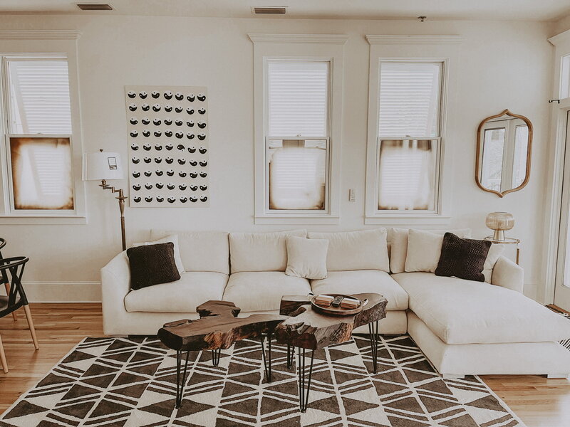 white modern living room with black accent rug and throws
