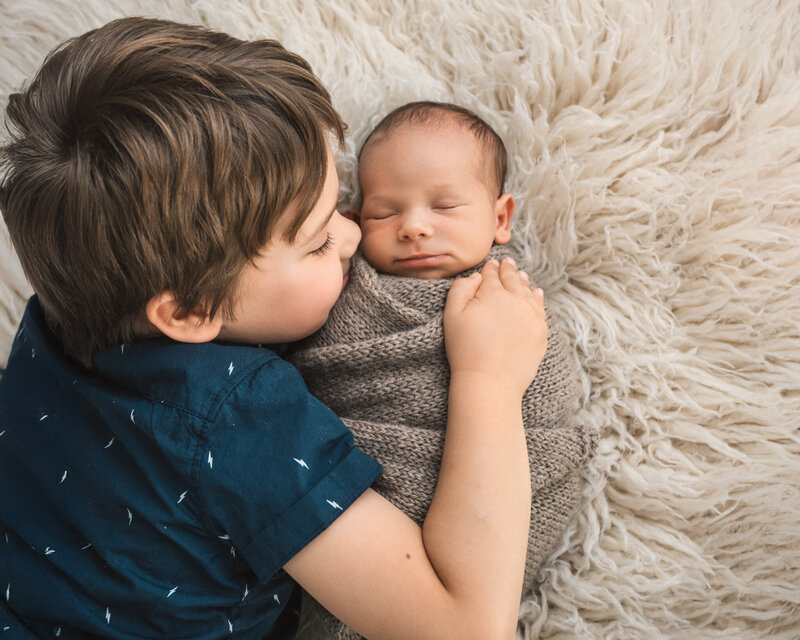 Baby boy in small bed wrapped and holding a knitted bunny