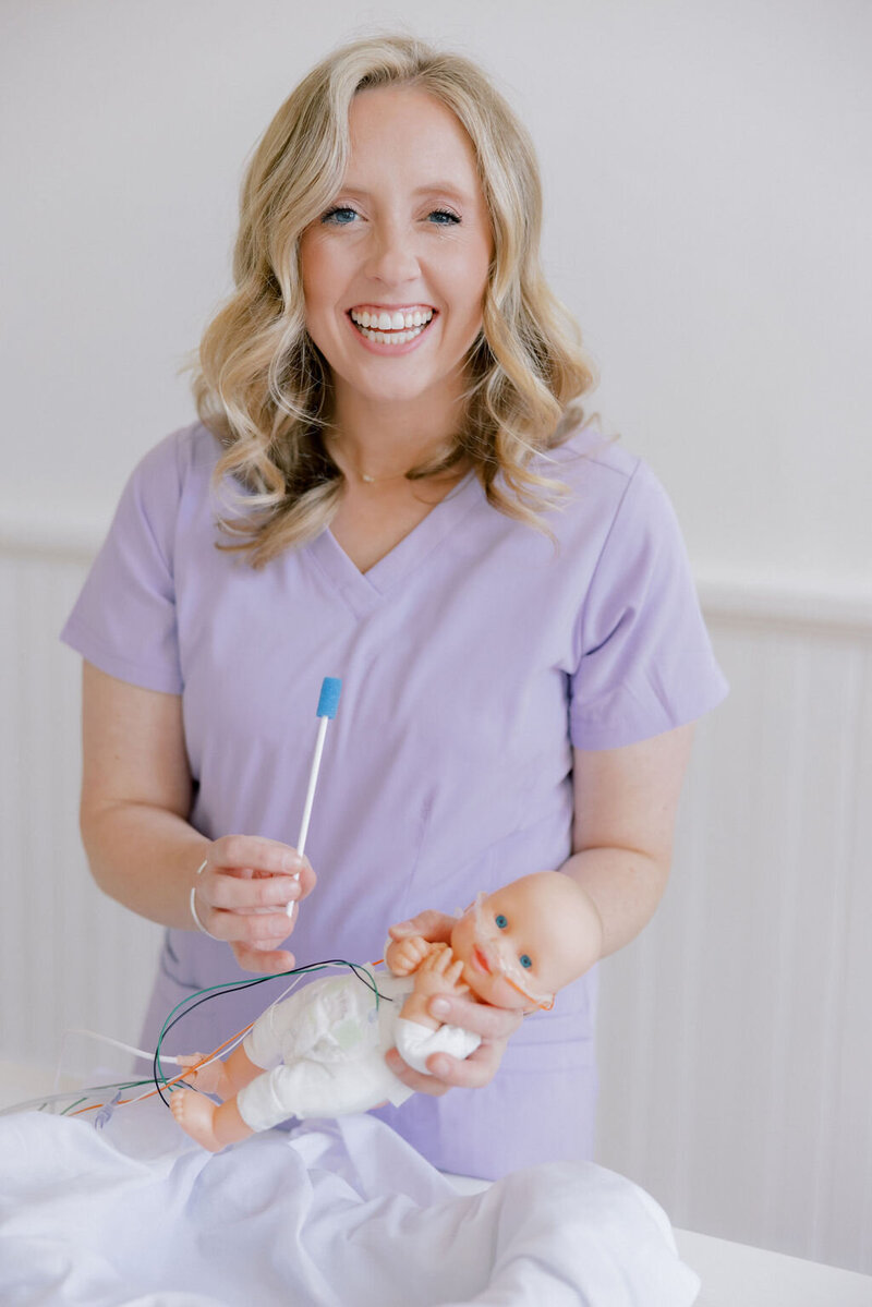 woman smiling while holding NICU baby and oral swab