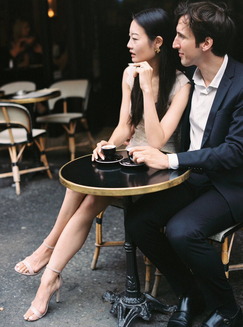 Chihiro and Giulio drinking Coffee in Cafe de Paris, near Palais Royal, detail view on the shoes, leg and couple