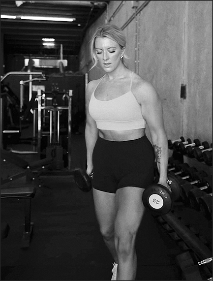 Black and white image of Kaylin unracking dumbells 
