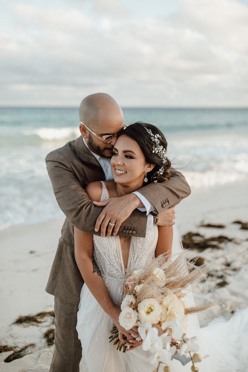 bride and groom embrace on beach