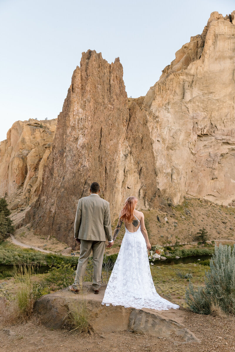 Couple holding hands and looking out at Smith Rock State Park in Oregon.