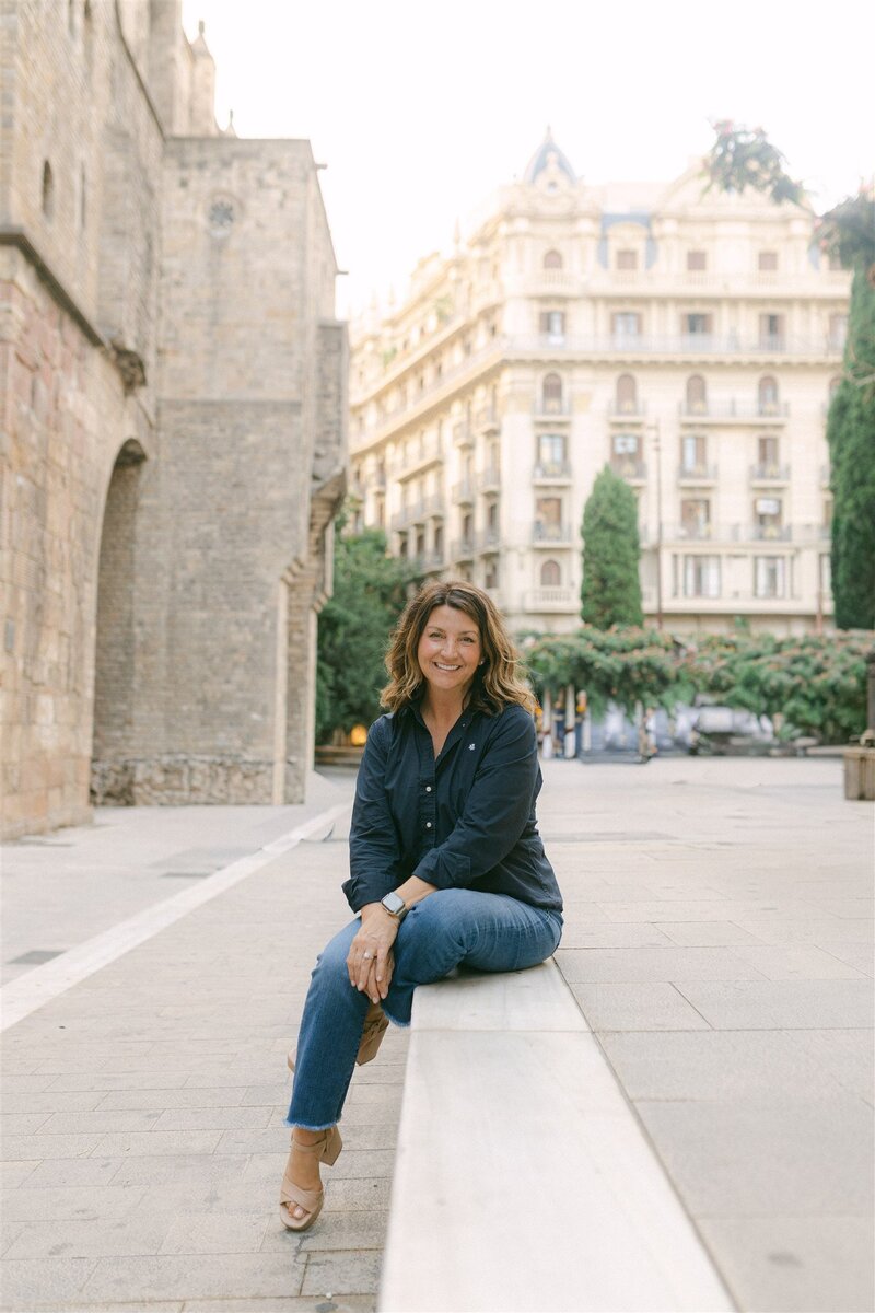 woman sitting on large stone steps outside by old stone buildings