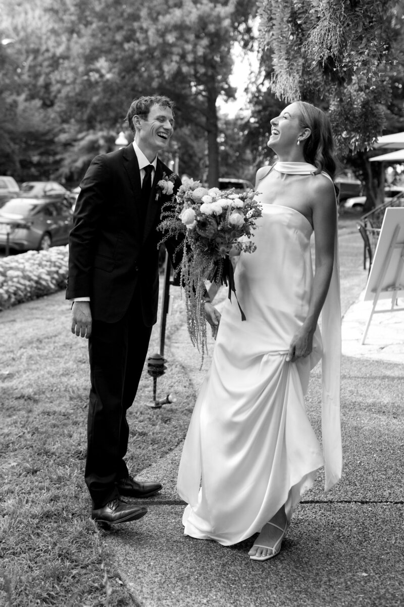 Black and white image of bride and groom smiling listening to toasts at their wedding reception in St. Louis