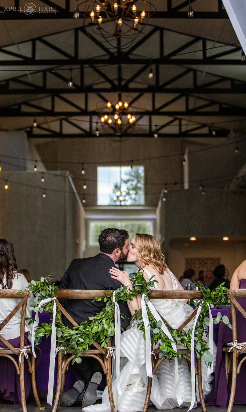 Couple Kiss at their Wedding Dinner Reception inside the Woodlands Barn in Colorado