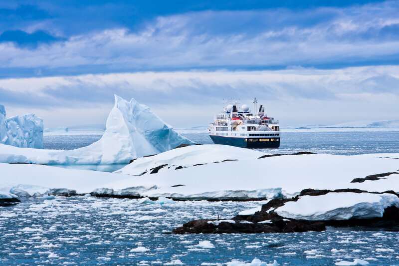 An expedition ship cruising through the icy waters of Antarctica surrounded by glaciers and ice.
