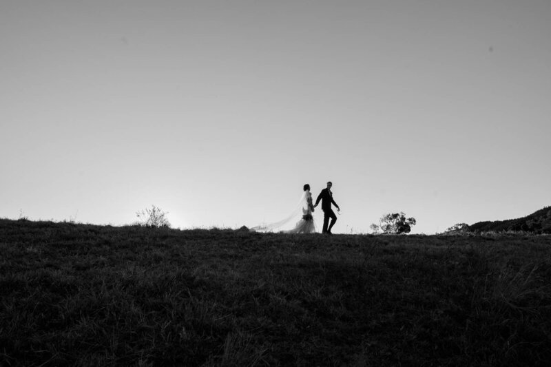 Newly-wed couple walking down the mountain slope while holding hands