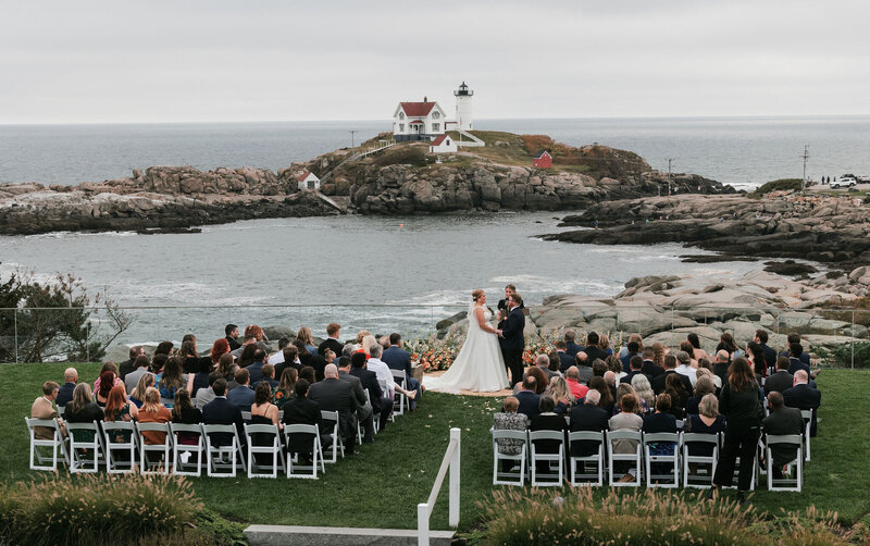 Wide shot of a wedding ceremony overlooking water and a lighthouse