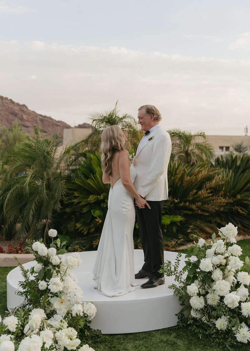 ride and groom exchanging vows in outdoor Arizona wedding ceremony with floral décor and desert scenery