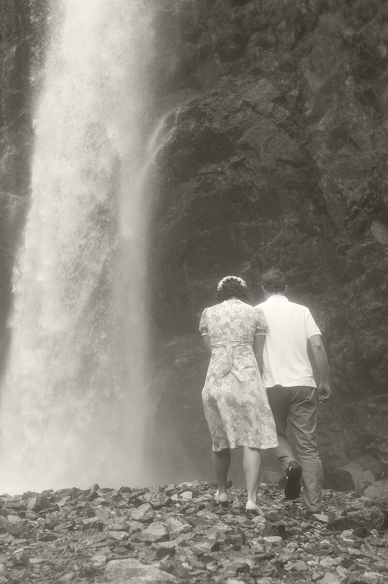 A couple walking under a waterfall together