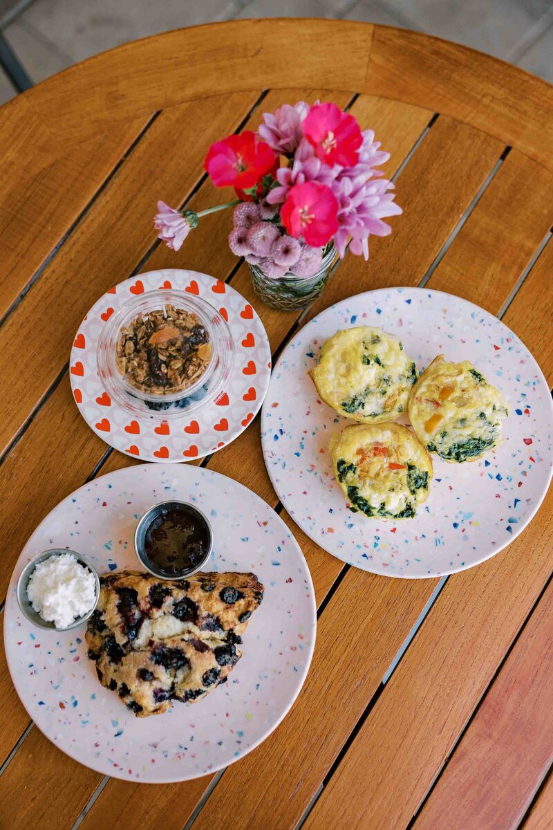 Breakfast spread with egg frittatas, a blueberry scone, and a yogurt parfait.