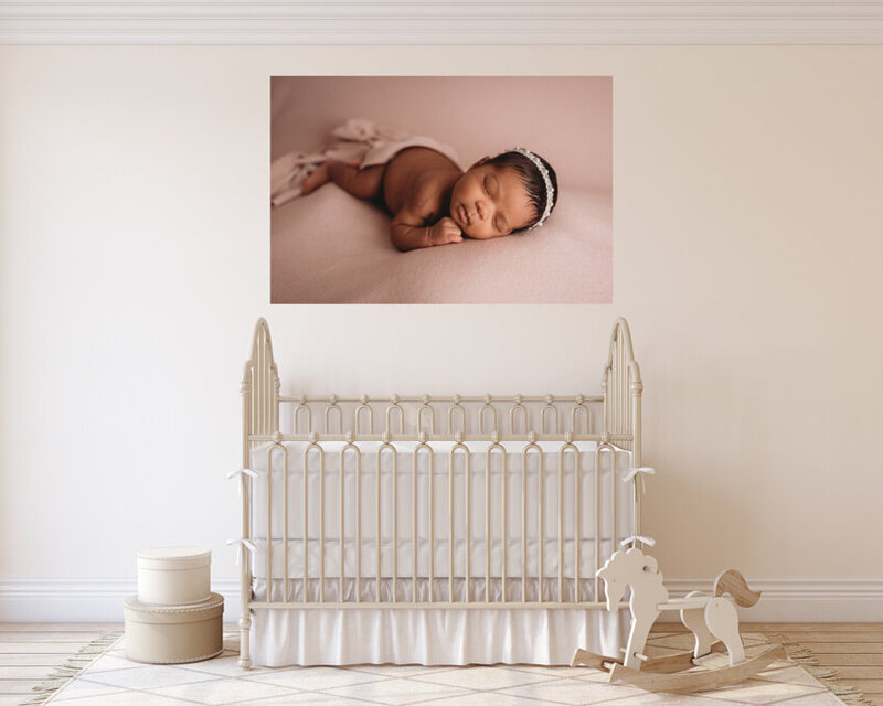 Atlanta, Georgia newborn photographer canvas artwork hanging in nursery with white walls and white furniture. Canvas artwork has image of newborn baby girl
