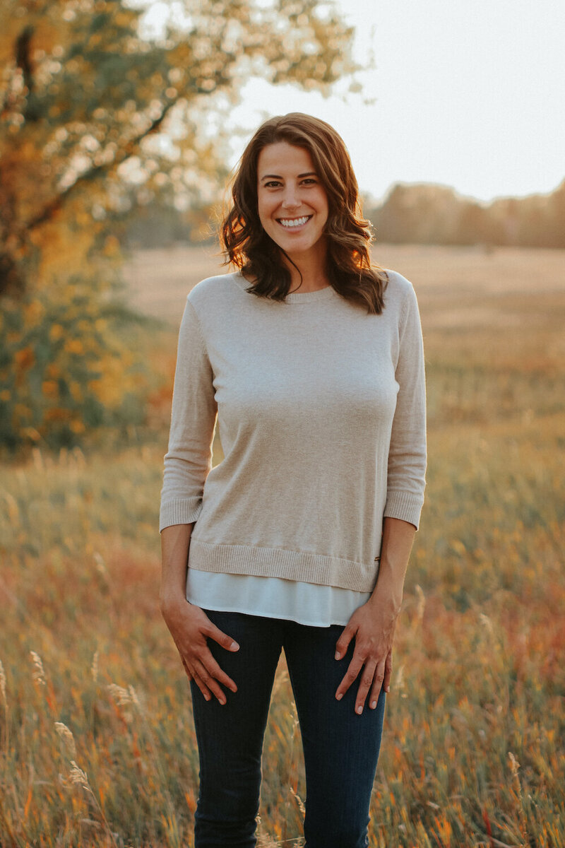 A woman stands in a field with a tree behind her, representing a nutritionist in Littleton, Colorado.