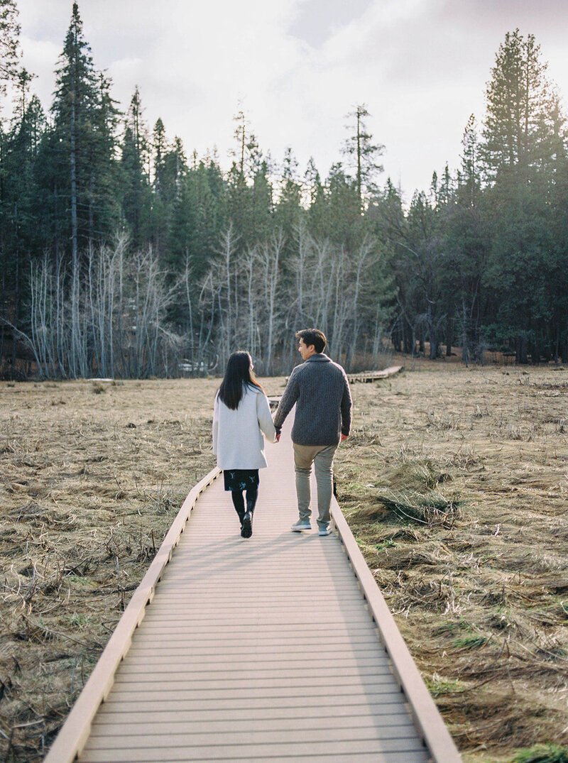 A couple strolls along a forest pathway during their engagement session in California, beautifully captured by Tiffany Longeway Photography