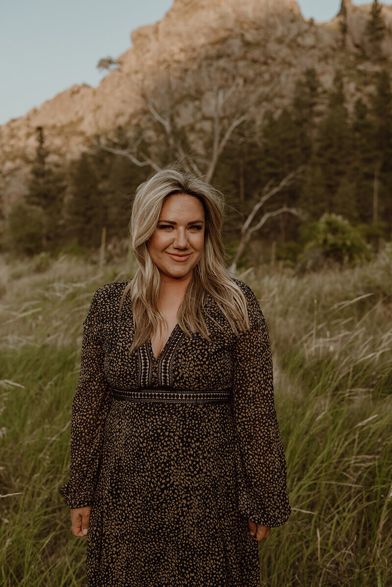 Photographer standing in grassy field with a mountain behind her in fort Collins colorado