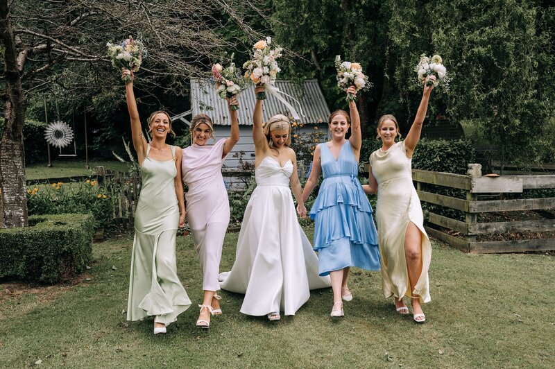 bridesmaids in mismatched pastel dresses walk with bride near gore southland
