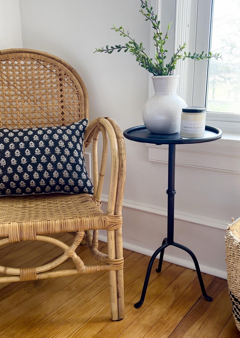 Rattan chair with decorative pillow and small black side table