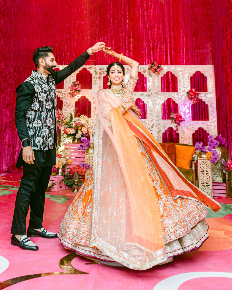 sikh bride and groom smiling while groom twirls the bride