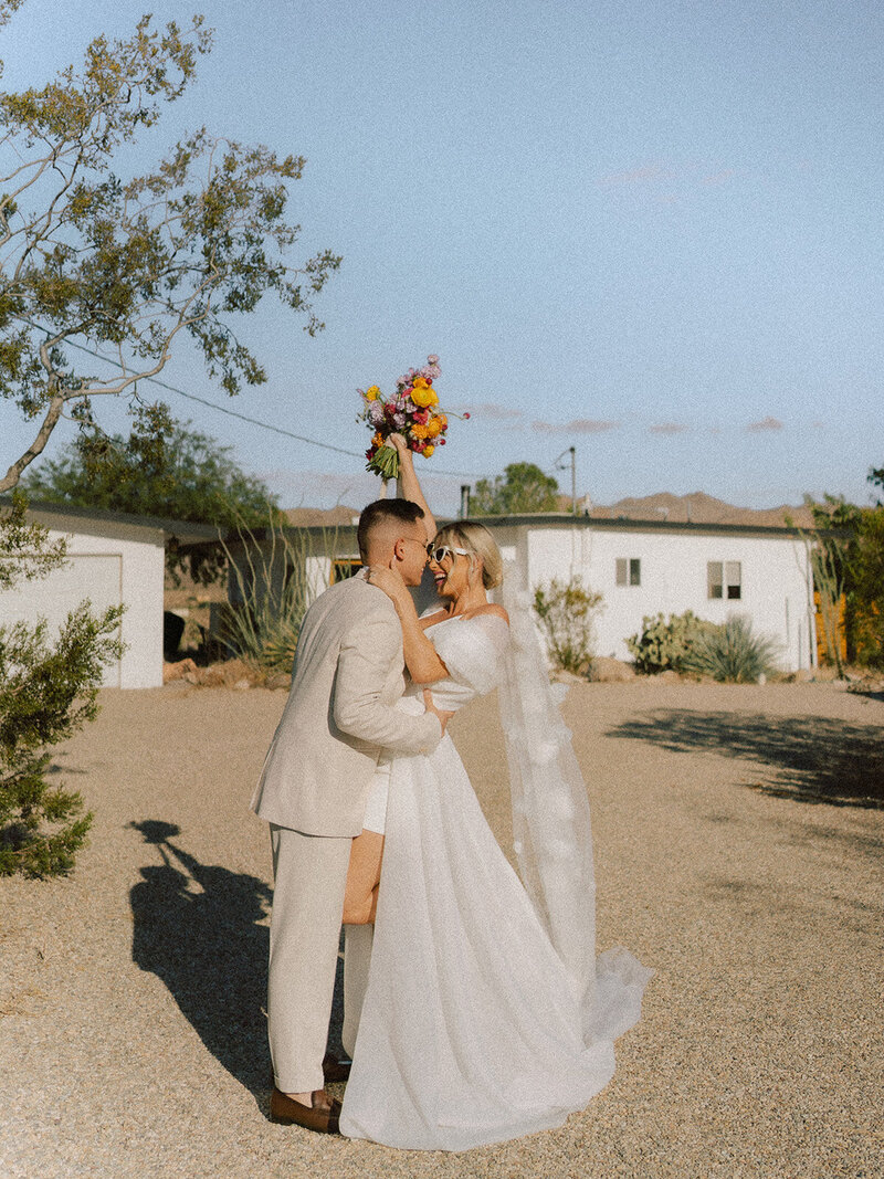 Bride and groom hug with colorful bouquet in the desert