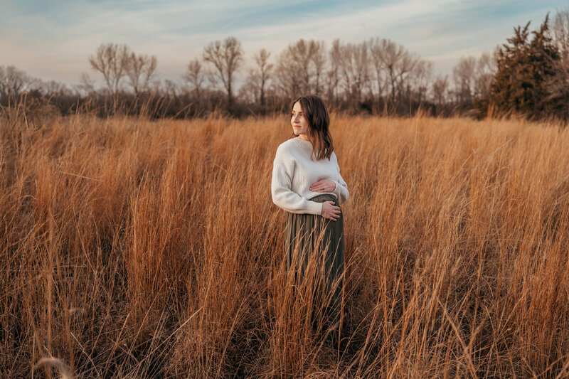 mom and dad kissing in field at sunset