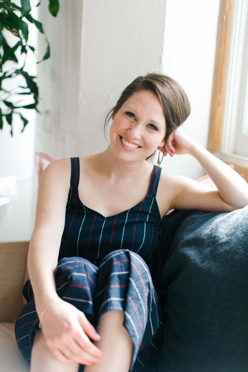 client experience strategist Caitlyn Gray sitting on a blue couch with her head resting on her hand