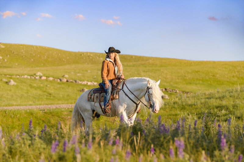 Horse and Rider, riding through field of purple lupine flowers in Montana. 