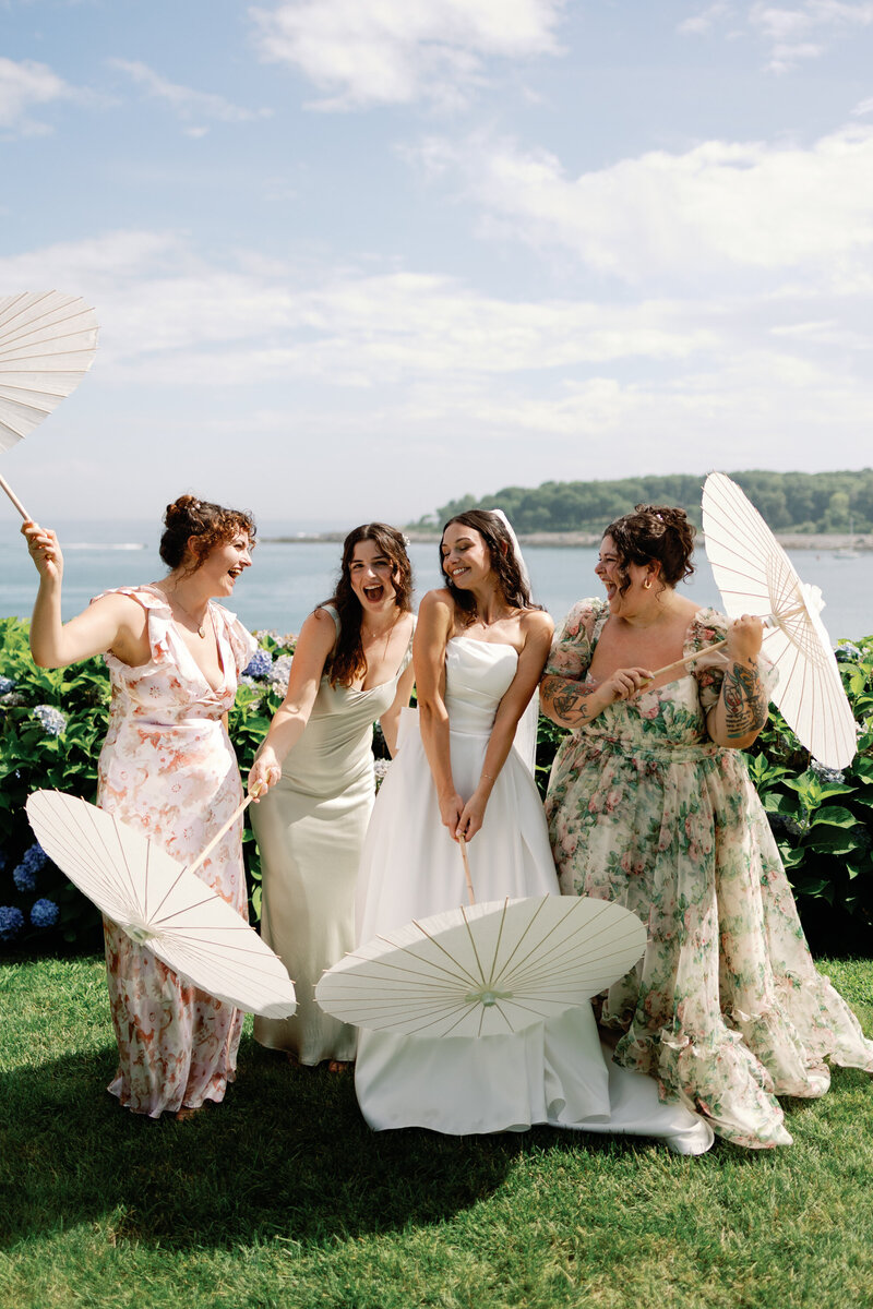 Bride and her bridesmaids wearing green floral dresses with dainty umbrellas