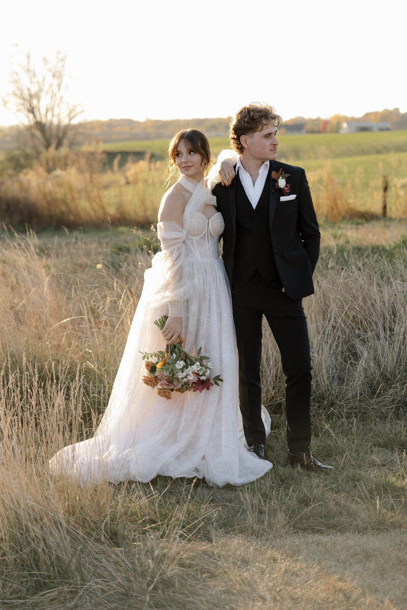 Editorial-style elopement photo with couple leaning together, surrounded by muted green grass.