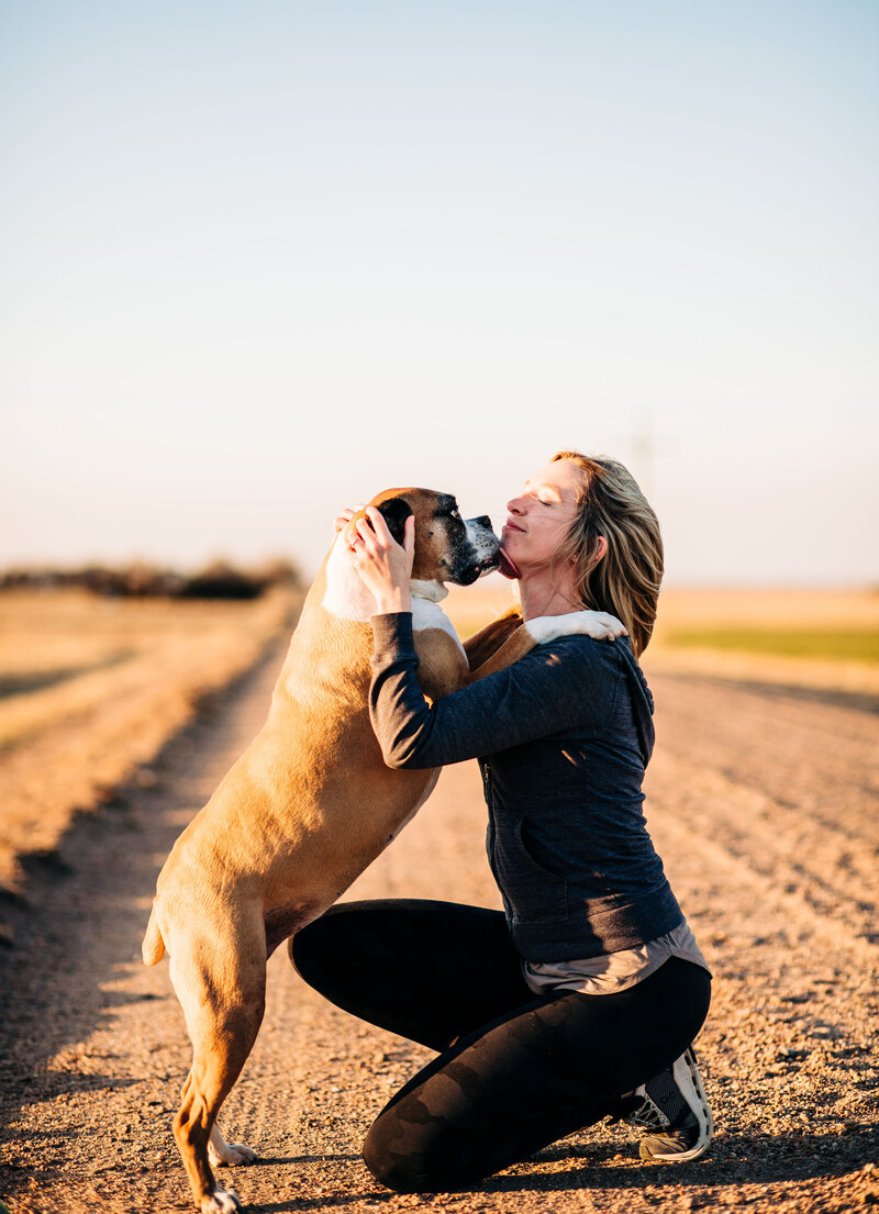 woman kissing her boxer dog