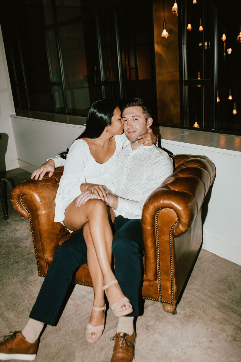 a woman kissing her boyfriends cheek while sitting on his lap