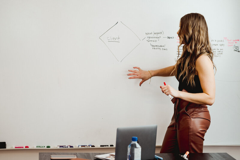 Woman presenting information off a whiteboard