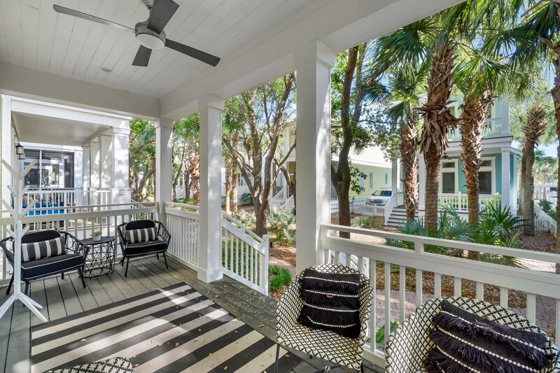 Stylish porch with striped rug, contemporary seating, and view of tropical landscaping