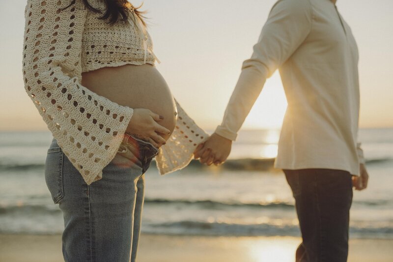 couple poses on beach at sunset