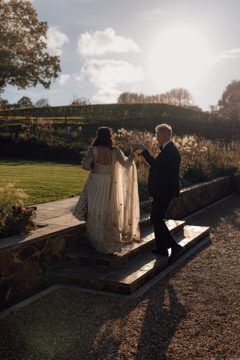 A portrait of Edward and Kristina walking arm in arm at the stunning front gardens of Hedsor House in the cotswolds