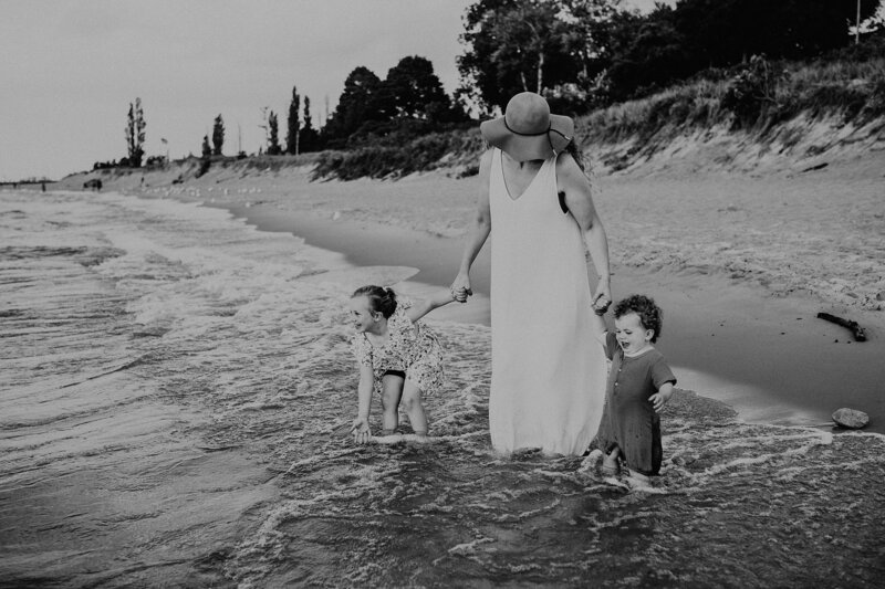 mom with young kids holding hands on beach