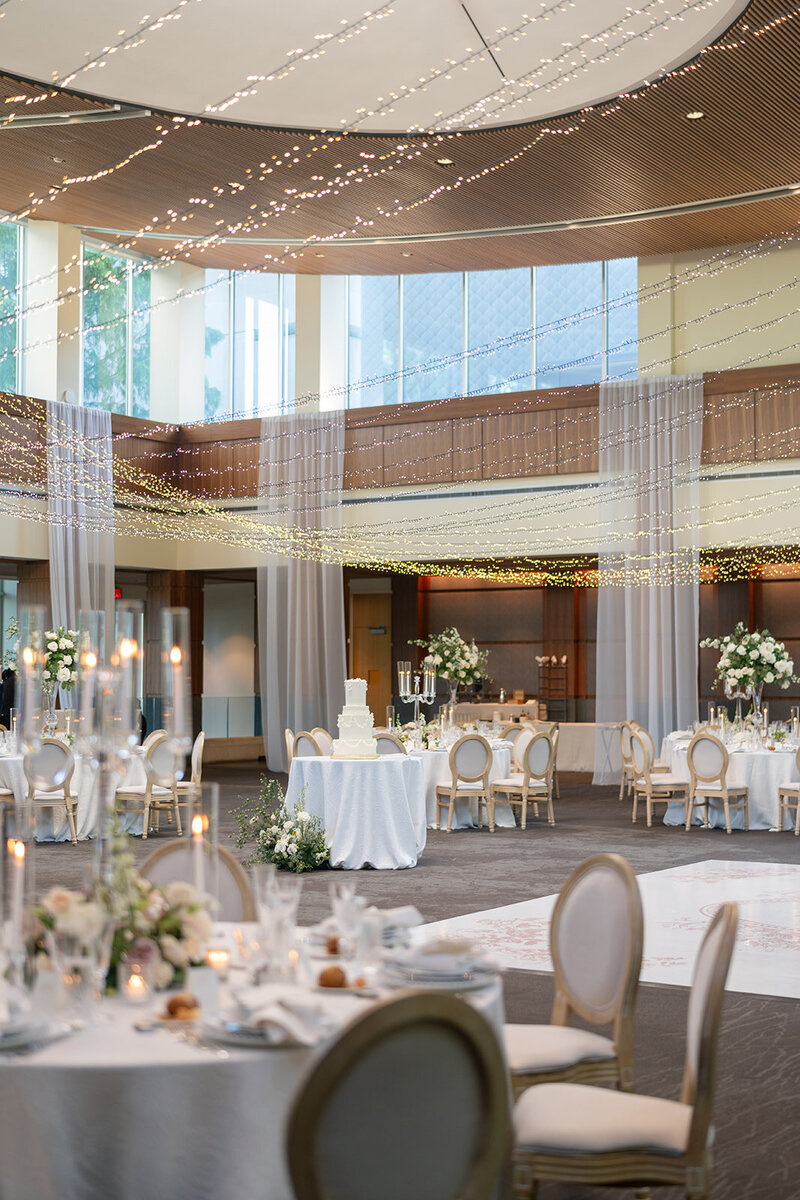 a wedding reception with white decor and string lights