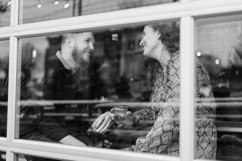 A couple laughs together during their engagement session