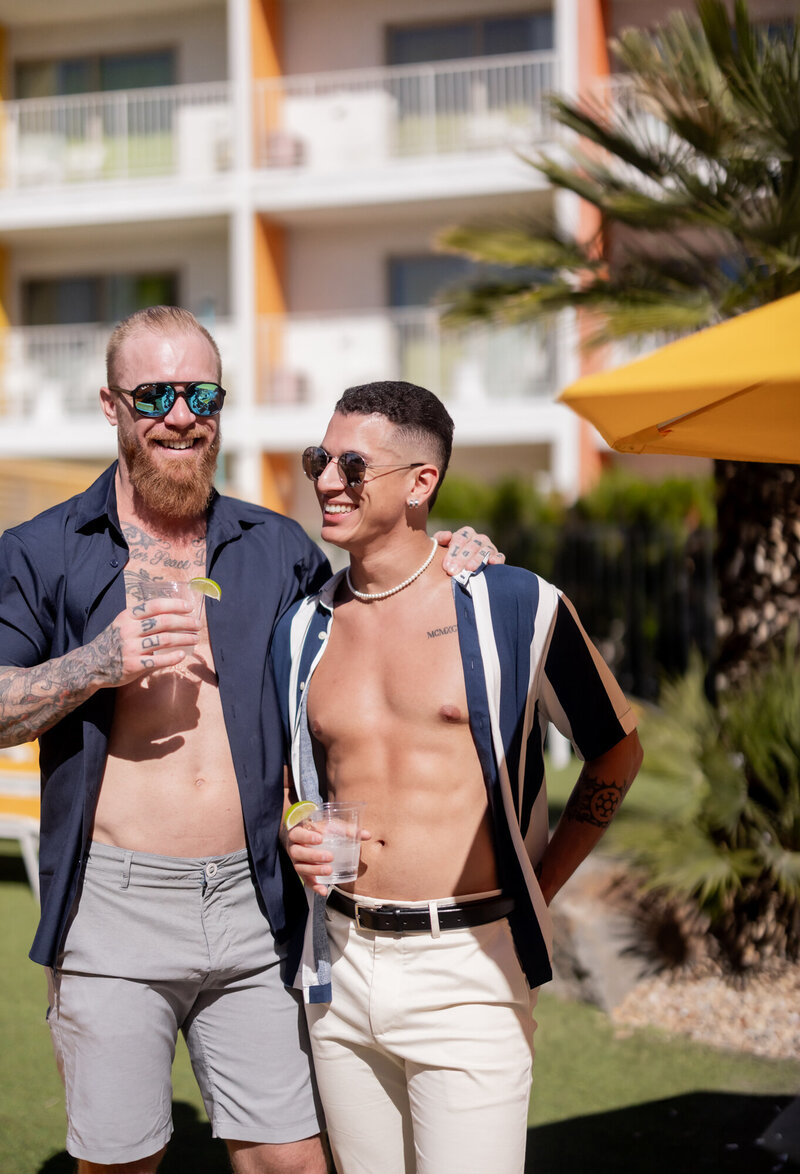 A stylish couple enjoys a sunny afternoon at a Palm Springs resort, dressed in effortlessly cool summer fashion. With sunglasses, cocktails, and mid-century modern architecture in the background, this vibrant image captures the carefree essence of a desert getaway.