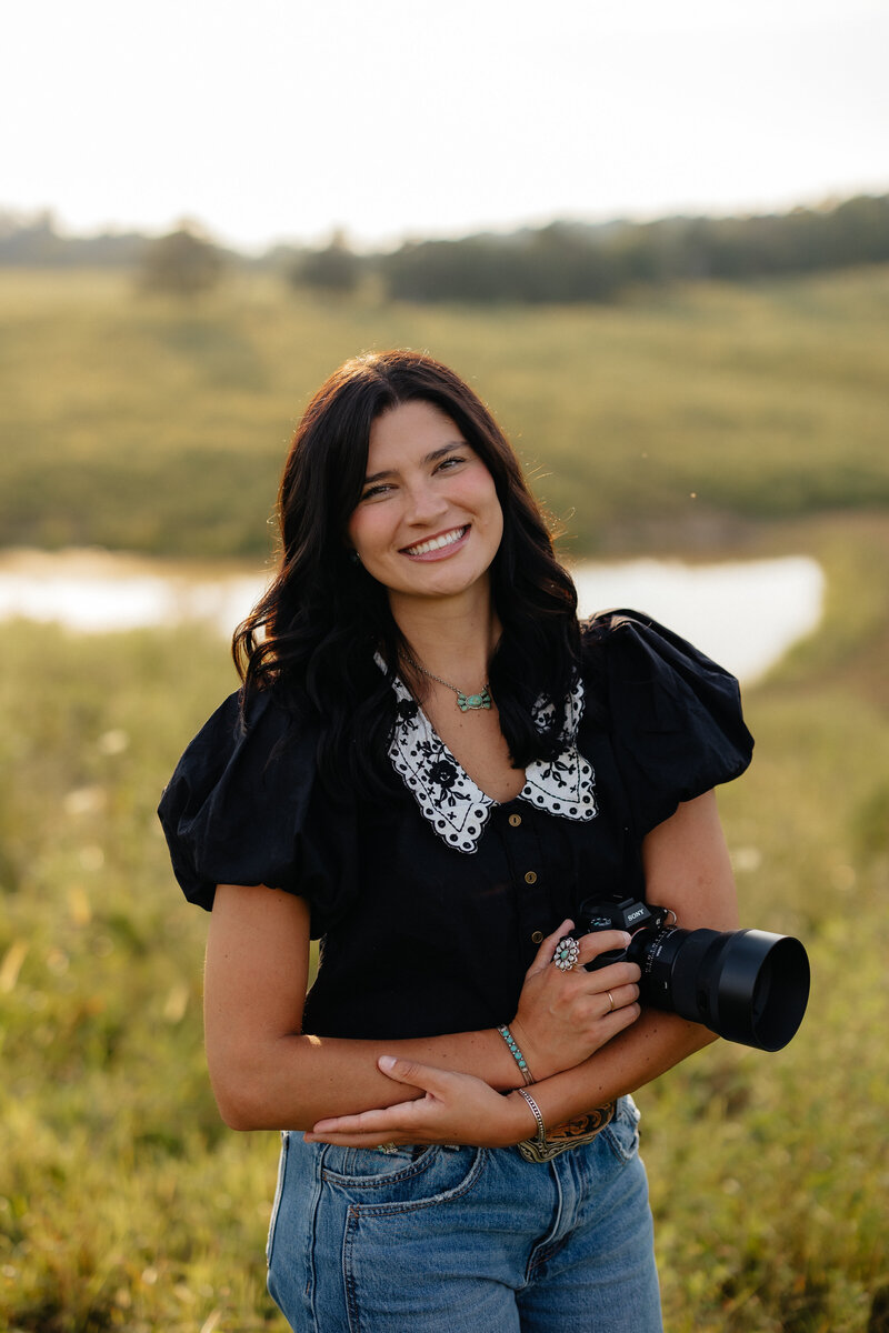 headshot of woman holding a camera in a field