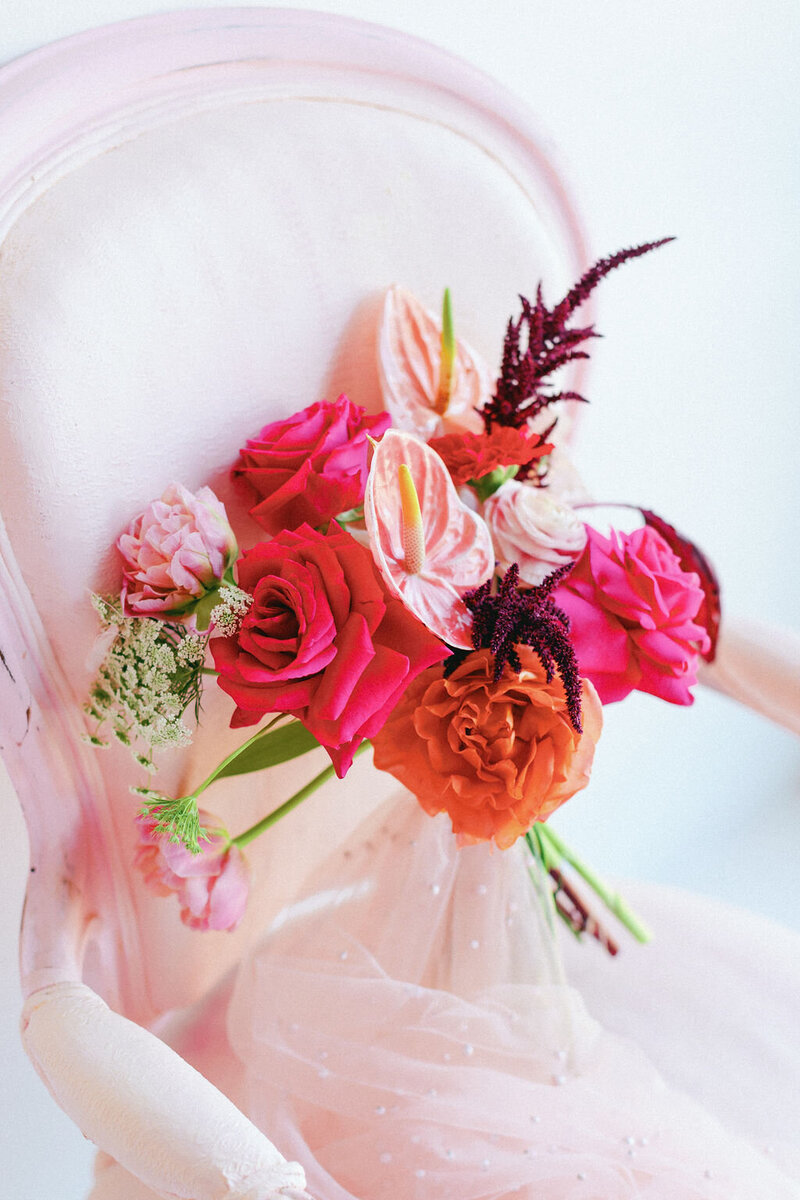 Pink and orange floral bouquet sitting on a chair