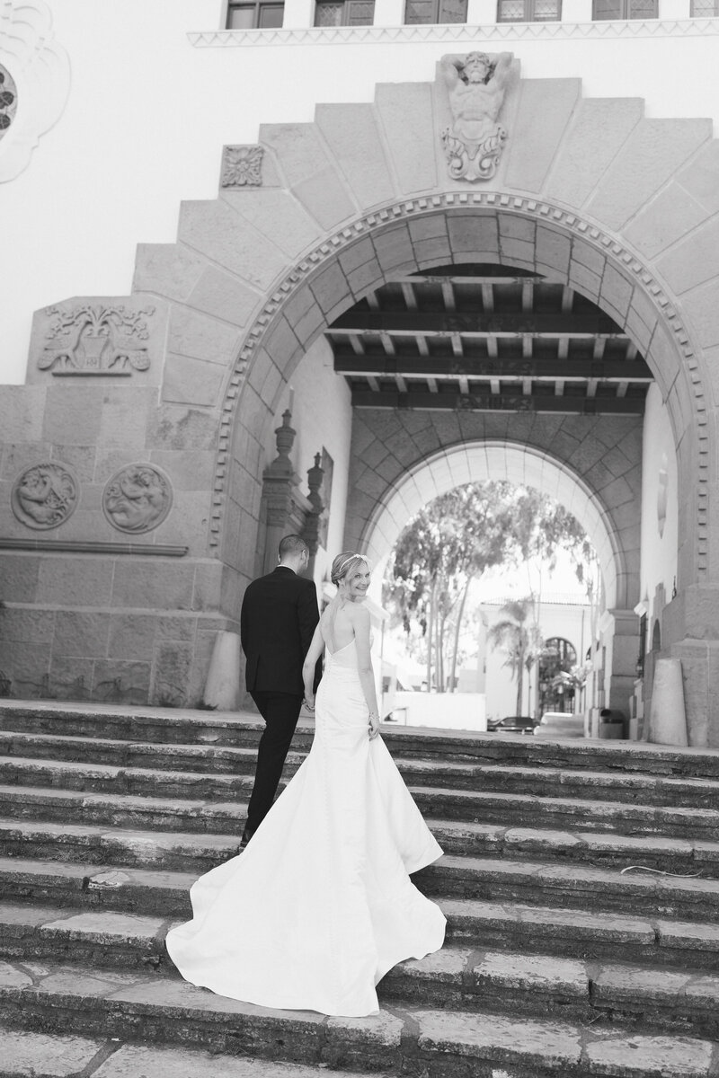 bride looks back at the camera on the grand staircase on anacapa street at the santa barbara courthouse