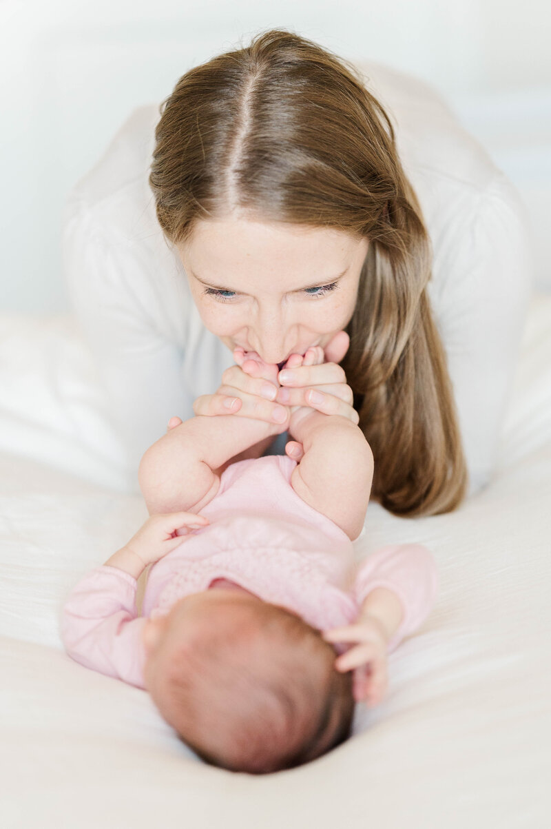 Newborn girl with mom kissing her toes taken in Westwood, MA by best Westwood newborn photographer