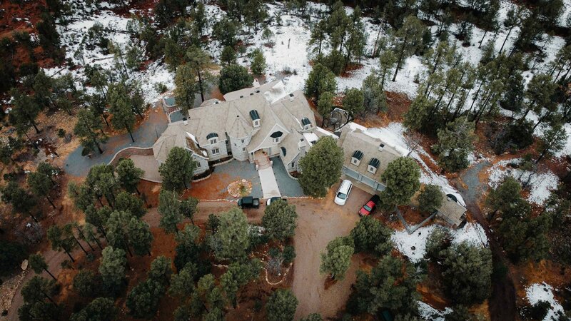 Aerial view of a beautiful chateau in the forest with a light dusting of snow covering the area. 