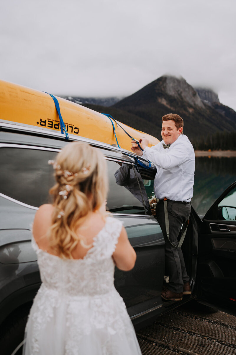 Elegant white and blush floral arrangement with roses, gerbera daisies, and eucalyptus in a glass vase on a wooden pedestal table.