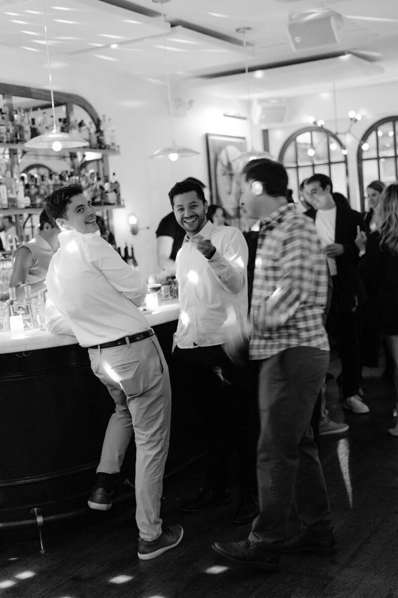 three men in button up shirts leaning on a bar