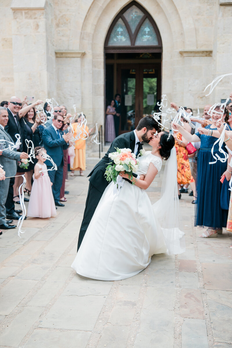 newlyweds kissing at end of aisle