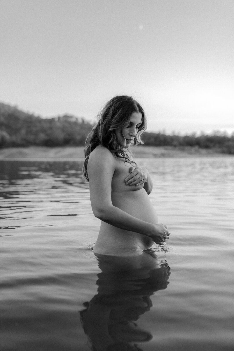 A pregnant woman standing in the water.
